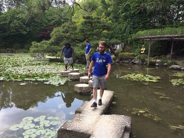 Three students walking on stones in a pond